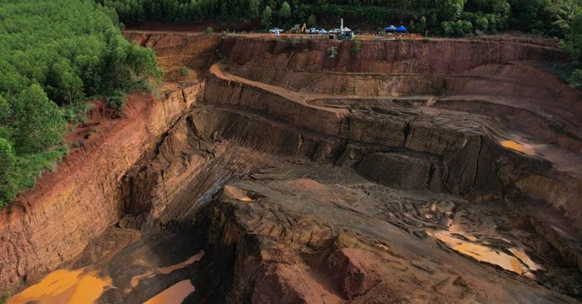 A large open pit with dirt and trees

AI-generated content may be incorrect.